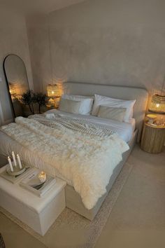 a large bed sitting in a bedroom next to two lamps and a table with candles on it