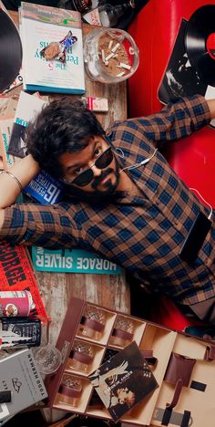 a man laying on top of a table covered in lots of records and other items