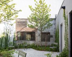 an empty courtyard with chairs and tables in the foreground, next to a brick building