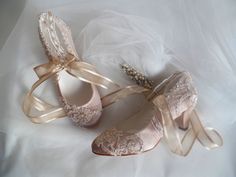 two pairs of wedding shoes on a white cloth covered surface with tulle and lace