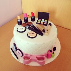 a white cake with makeup and other items on the top is sitting on a table