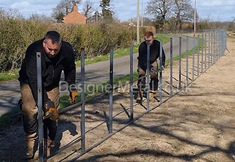 two men are working on metal posts in the dirt