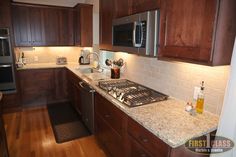 a kitchen with dark wood cabinets and granite counter tops, stainless steel appliances and an oven