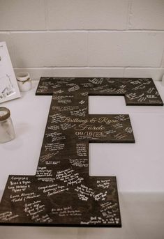 a wooden letter with writing on it sitting on top of a table next to a candle