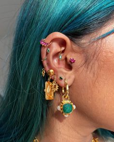 a close up of a person with blue hair and ear piercings on their ears