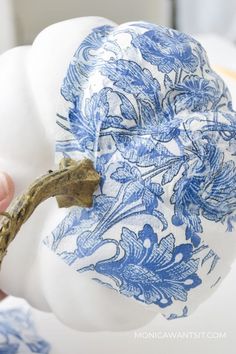 a close up of a blue and white vase being held by a person's hand