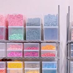 there are many plastic bins on the shelves with different colors and shapes in them