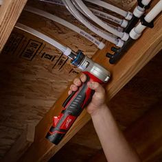 a person holding a drill in their hand and some wires on the wall behind them