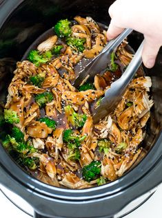 someone spooning broccoli and mushrooms into the slow cooker