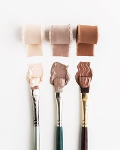 four brushes with different shades of paint on them