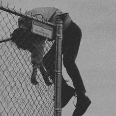 a man climbing up the side of a fence with his hand on top of him