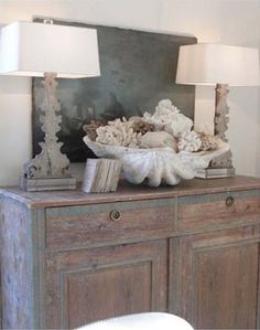 a table with two lamps on top of it next to a wooden cabinet and chair