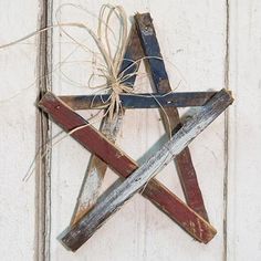 a wooden star hanging on the side of a white building with twine tied to it