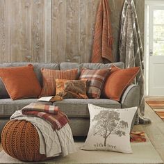 a living room filled with lots of pillows and blankets on top of a gray couch