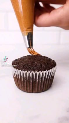 a cupcake being decorated with chocolate frosting and a pen sticking out of it