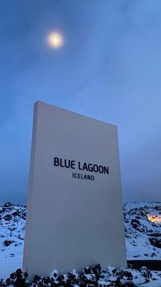 the blue lagoon sign in iceland is lit up at night with snow on the ground