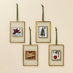 four framed christmas cards hanging on a wall with green string and twine around them