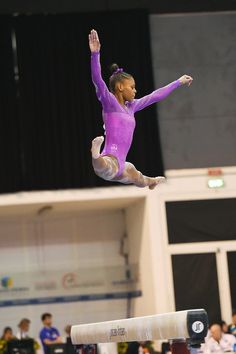 a woman on the balance beam in an indoor competition