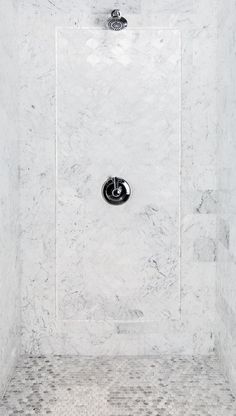 the shower head is mounted to the wall in this bathroom with white marble walls and flooring