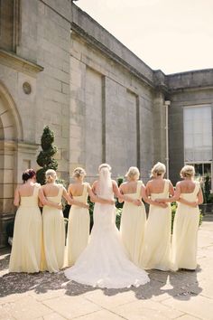 a group of bridesmaids standing in front of a building with their backs to the camera