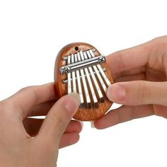 two hands are holding a small wooden toy with musical instruments on it's sides