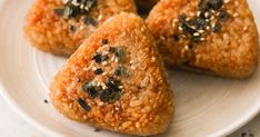 three pieces of food on a plate with sesame seeds and seasoning sprinkles