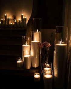 lit candles sit on a table in front of a stairway with flowers and candles around it