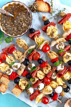 an assortment of food on skewers with dipping sauce