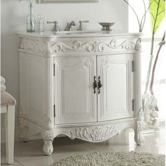 a white bathroom vanity with a mirror above it and a rug on the floor next to it