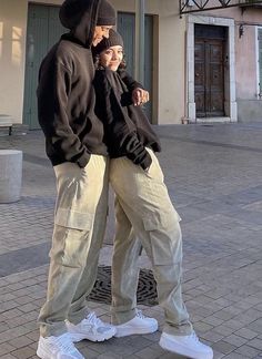 two people standing next to each other in front of a building