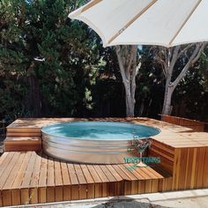 an above ground pool with wooden decking and umbrella