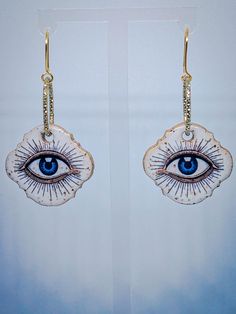 These handmade speckled ceramic pendant earrings are truly one-of-a-kind, featuring striking blue eyes as the central design. The eyes are detailed with rays shooting outward, giving the earrings a mystical and almost celestial feel, as if each eye holds a secret or ancient wisdom. The speckled ceramic finish adds texture and character to the piece, making each pair unique, while the vivid blue of the eyes stands out against the more earthy tones of the speckled ceramic background. Suspended fro Artistic Dangle Jewelry For Festivals, Symbolic White Jewelry For Festivals, Bohemian Evil Eye Jewelry For Festivals, Bohemian Style White Single Earring, Mystical Handmade Teardrop Earrings, White Bohemian Pierced Jewelry, Bohemian Evil Eye Dangle Jewelry, Bohemian Evil Eye Earrings As Gift, Unique Evil Eye Jewelry For Festival