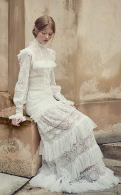 a woman in a white dress sitting on a ledge