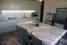 a kitchen with marble counter tops and white cabinets