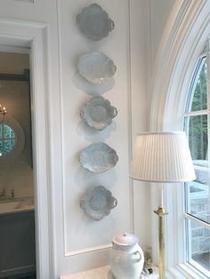 plates are hanging on the wall next to a table with a lamp and vase in front of it