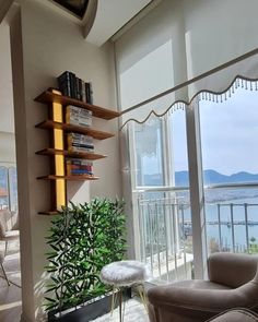 a living room filled with furniture and a large window next to a wall mounted book shelf