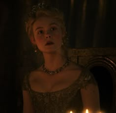 a woman in a gold dress holding a lit candle