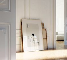 an empty room with white walls and wooden flooring, framed artwork on the wall