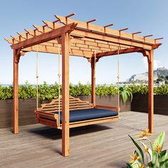 an outdoor swing bed with blue cushions on a wooden deck next to plants and flowers