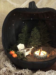 a miniature pumpkin shaped like a chair and fire in the ground with small trees inside