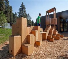 a young boy standing at the top of some stairs made out of wood blocks in front of a building