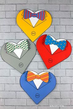 four heart shaped paper cut outs with bow ties and collars on them, hanging from a brick wall