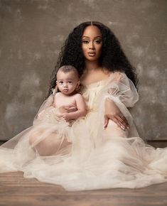 a woman holding a baby in her arms and wearing a dress with ruffles on it