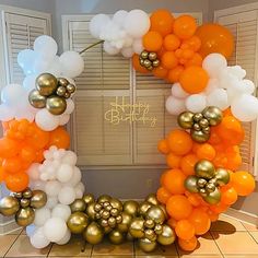 an orange, white and gold balloon arch