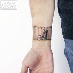 a person with a tattoo on their wrist is holding the hand of another person that has a birdcage behind them