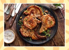 two pieces of meat on a plate next to silverware and utensils with an orange background