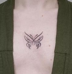 a woman's chest with a small black bird tattoo on the left side of her chest