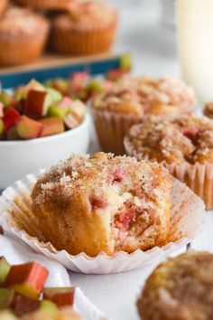 some muffins are sitting on a table next to bowls of fruit