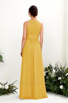 a woman in a long yellow dress looking back at the camera, with white flowers behind her