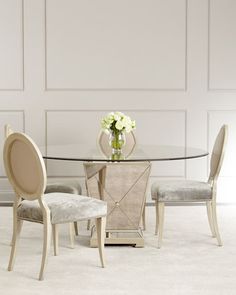 a glass table with chairs around it and a vase on the table in front of it